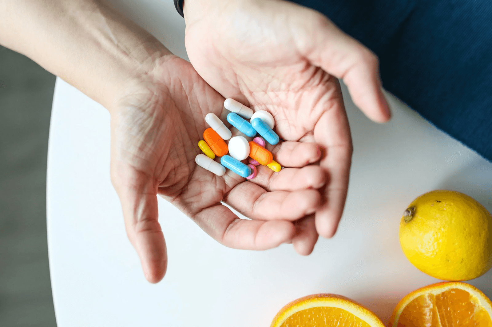 Hands holding vitamins in several different colours and shapes