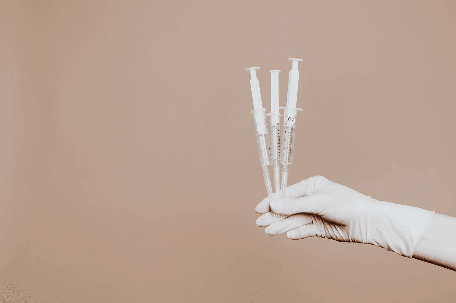 hand holding three syringes