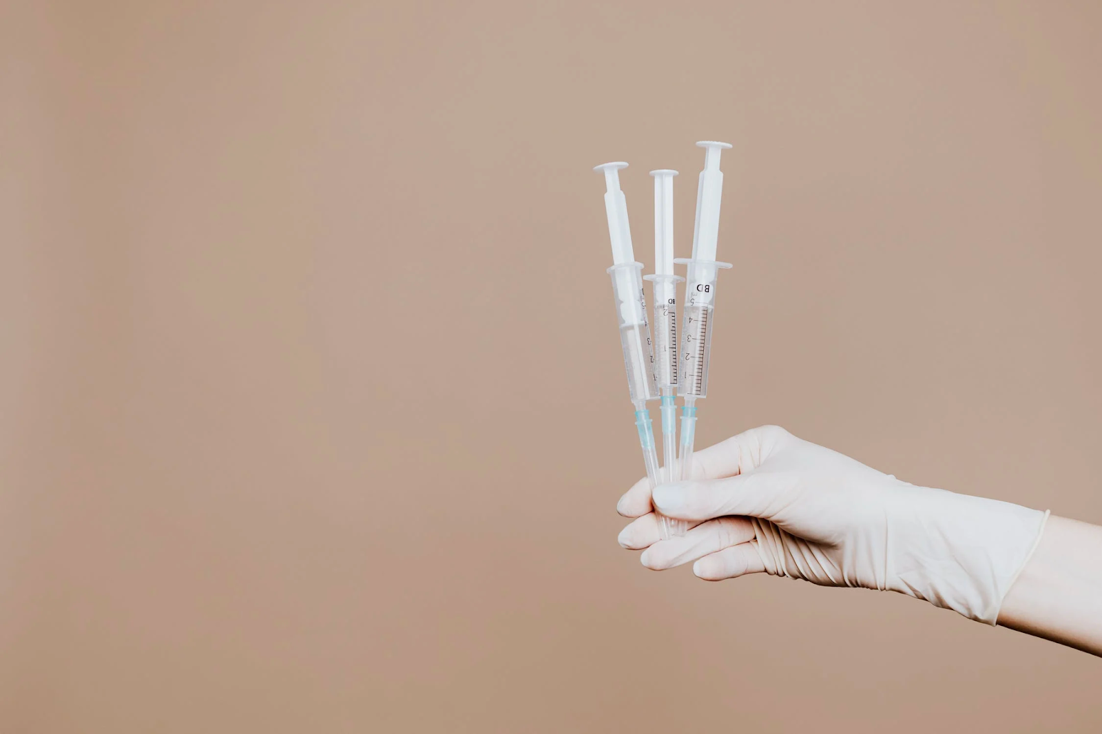 hand holding three syringes